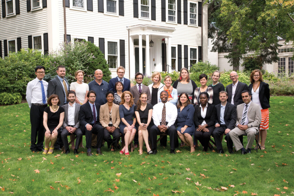 A group of people pose for an picture on the lawn of a white house.