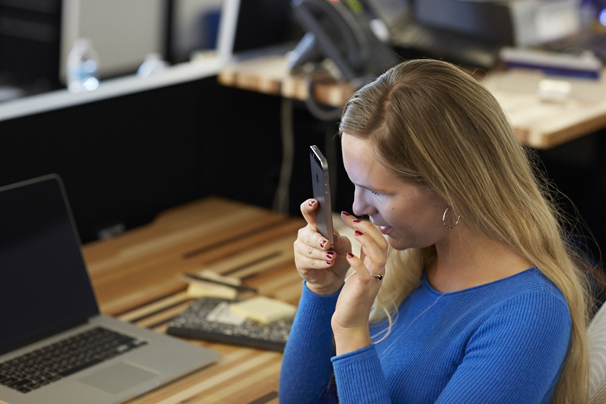 A woman in a blue sweater holds a smart phone close to her face at Yahoo's accessibility research lab