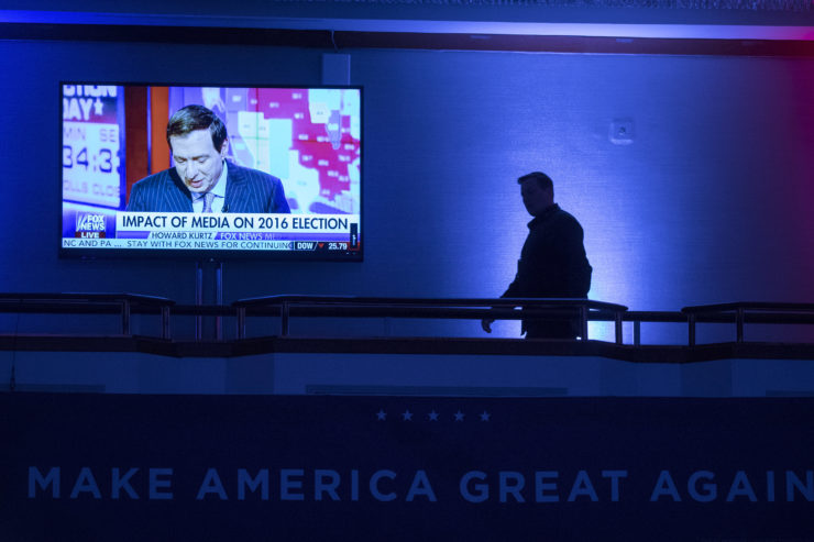 A member of the media walks near a monitor displaying election coverage during preparations for Trump's election night rally in New York