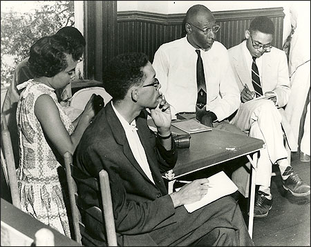 Simeon Booker, in the dark jacket, covers the Emmett Till murder trial for Jet magazine in 1955. He is seated in the Negro press section with, from left, Clotye Murdock of Ebony, L. Alex Wilson of The (Memphis, Tenn.) Tri-State Defender, and Steve Duncan of The St. Louis Argus