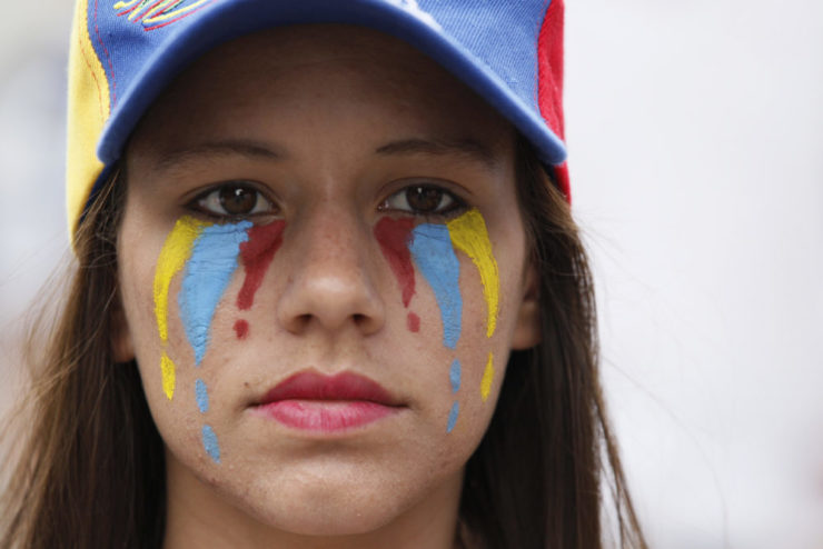 More than 60 people have been killed in the latest wave of protests in Venezuela this spring, with hundreds of others—including journalists—injured. Here, a woman with her face painted in the colors of Venezuela's national flag attends a silent protest in homage to those killed 