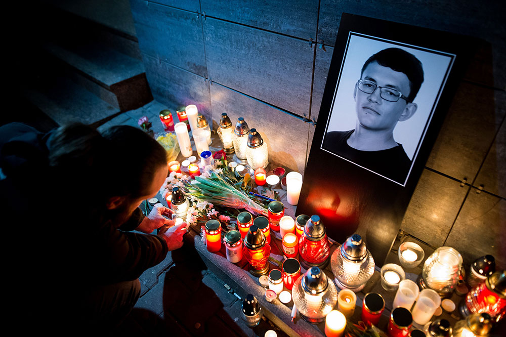 A man lights a candle at a memorial for Ján Kuciak, the Slovak journalist murdered in
February 2018, in front of the Aktuality.sk office in Bratislava