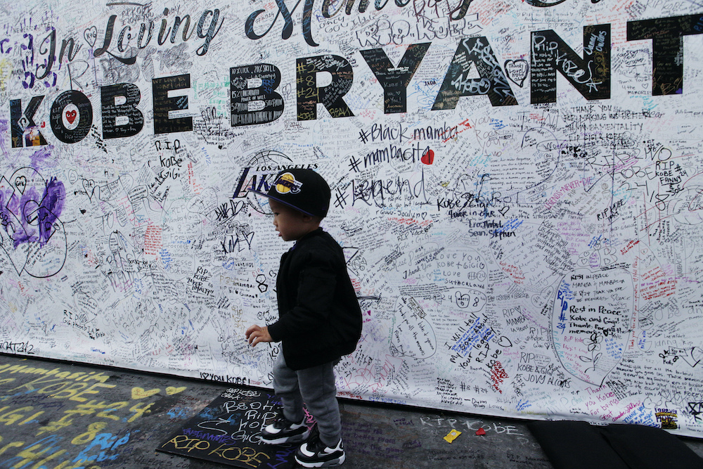 A boy walks by a standing board with messages for the late Kobe Bryant at a memorial.