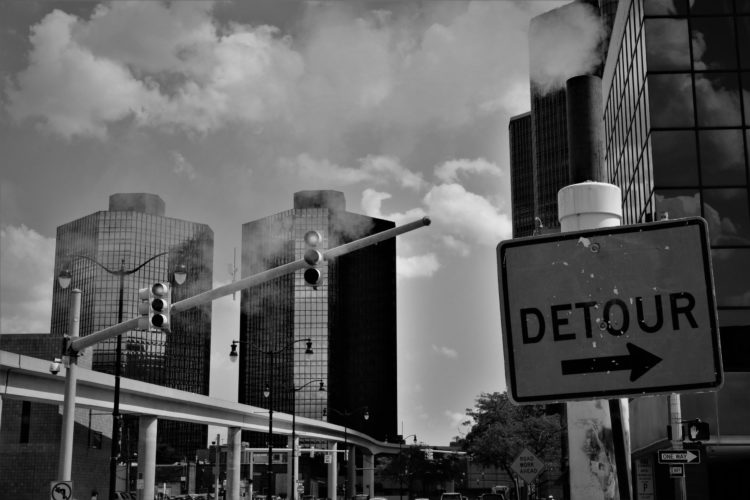 Stock image of a city with a detour sign in the foreground