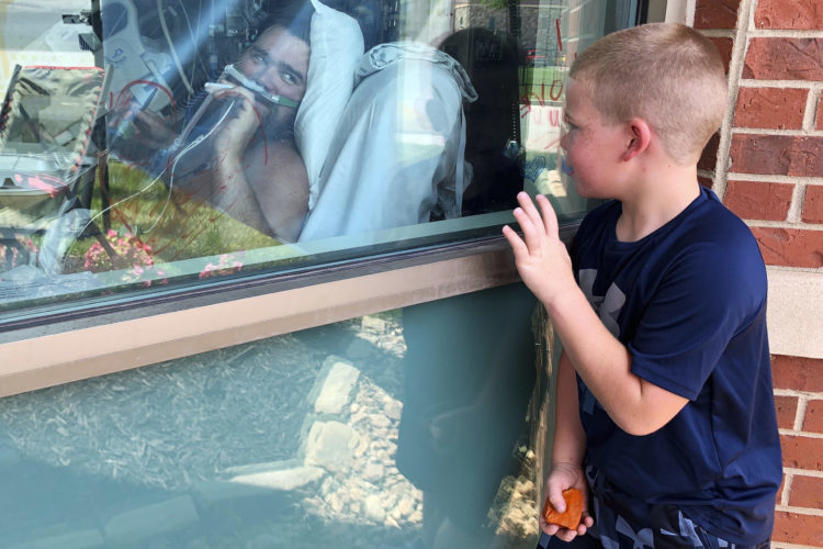 A boy waved through the window to his father, who was recovering from COVID-19 in an Osage Beach, Mo., hospital in July 2021.
