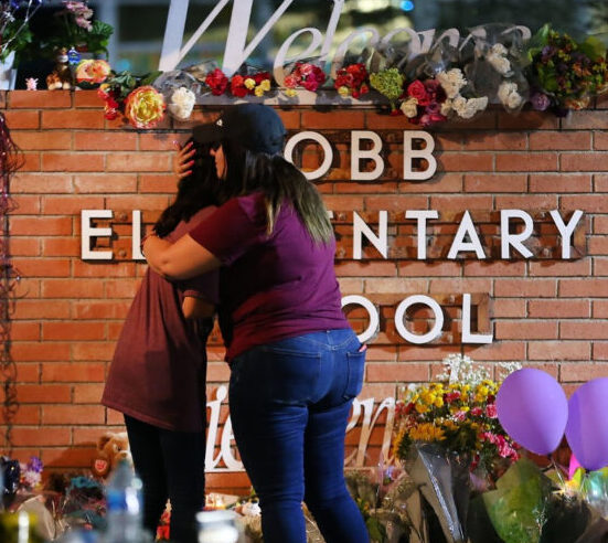 Two people embrace in front of a memorial at the Robb Elementary School in Uvalde, Texas, the scene of a mass shooting in May 2022.